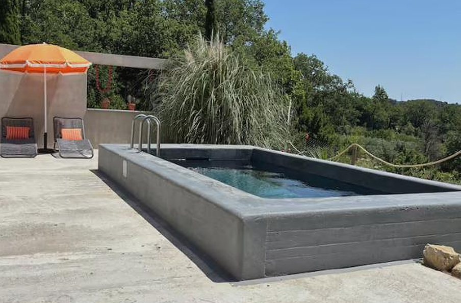 Piscine face aux collines avec parasol orange